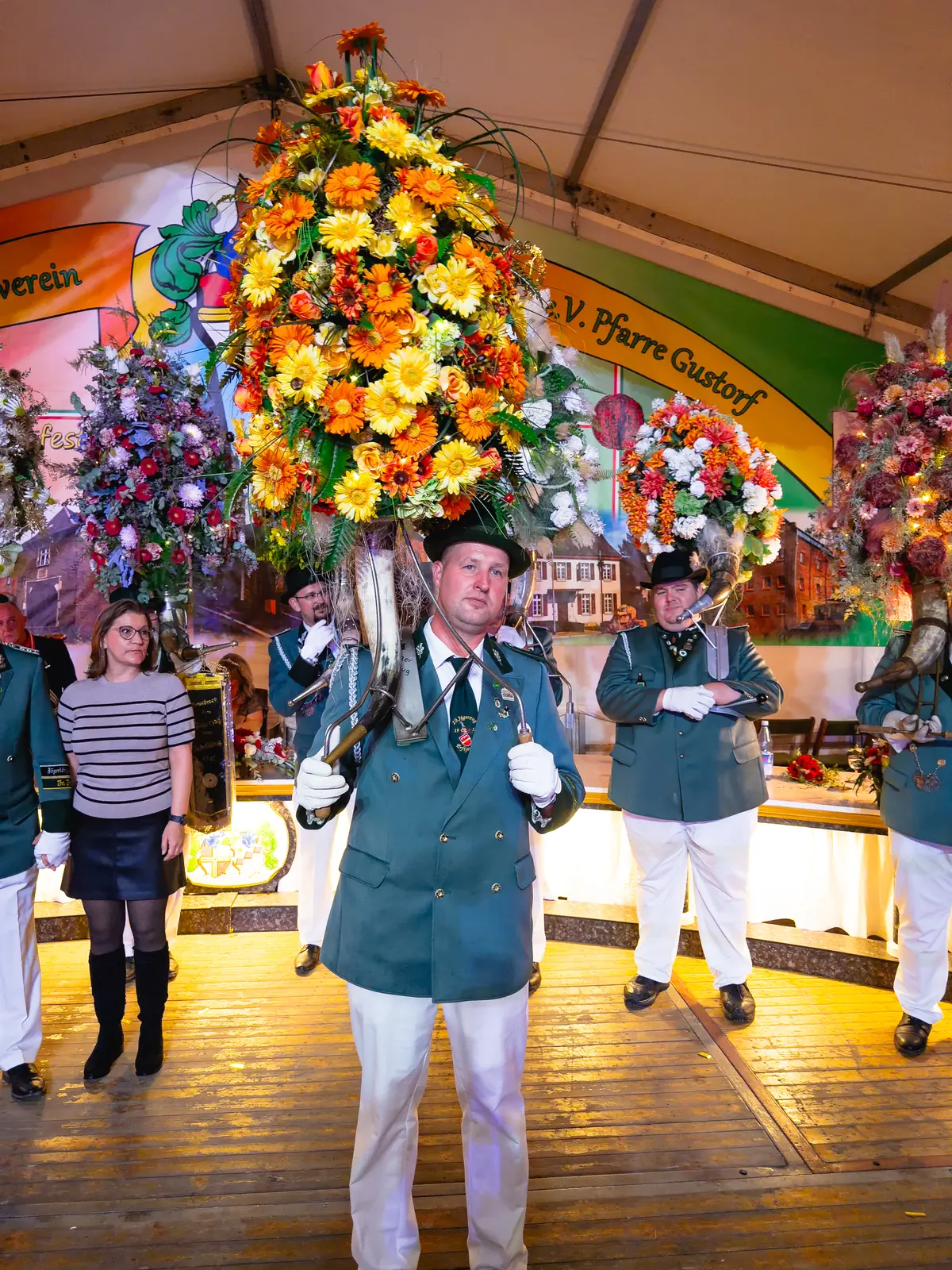 Schütze in grüner Uniform mit einem großen orange-gelben Blumenschmuck.